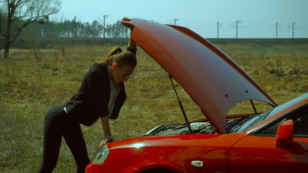 Sexig tjej ser ut under huven på en sportbil — Stockvideo