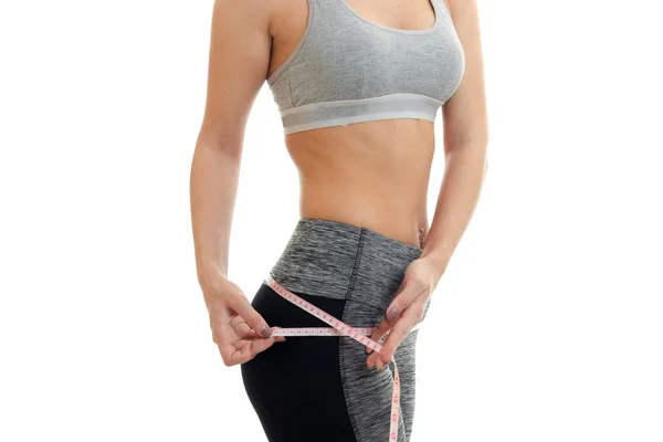 Slender sport girl in grey top measures hips band close-up — Stock Photo, Image