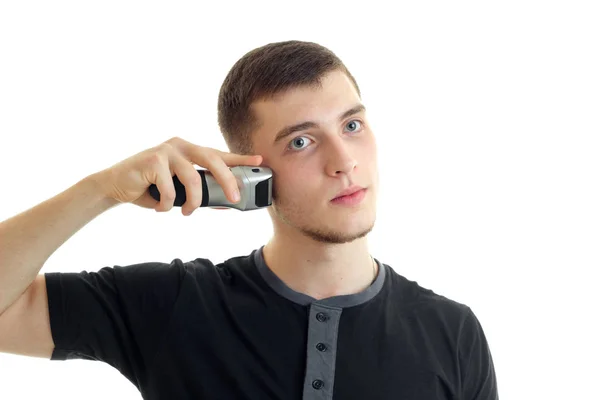 Portret van een jonge man in een zwart t-shirt die met een ernstig gezicht close-up scheert — Stockfoto