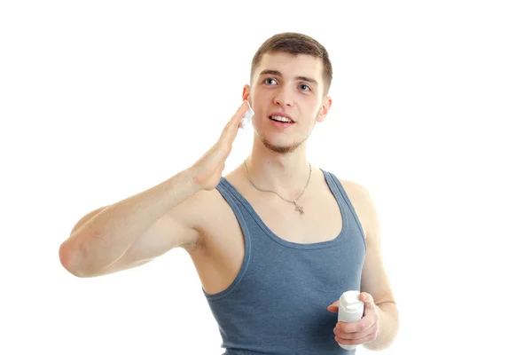 Funny young guy in the gray shirt looks into the distance smiling and causes the foam to your face — Stock Photo, Image