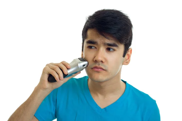 Giovane ragazzo forte in una t-shirt guardando lateralmente e radere un trimmer barba è isolato su uno sfondo bianco — Foto Stock