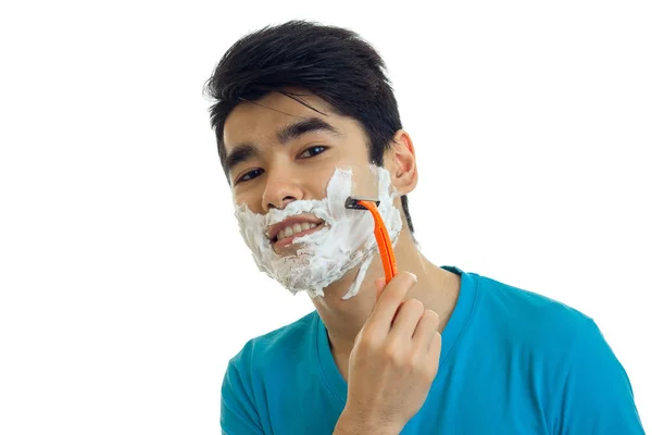 Ritratto di un giovane sorridente con la schiuma sul viso che si depila la barba e guarda la telecamera da vicino — Foto Stock