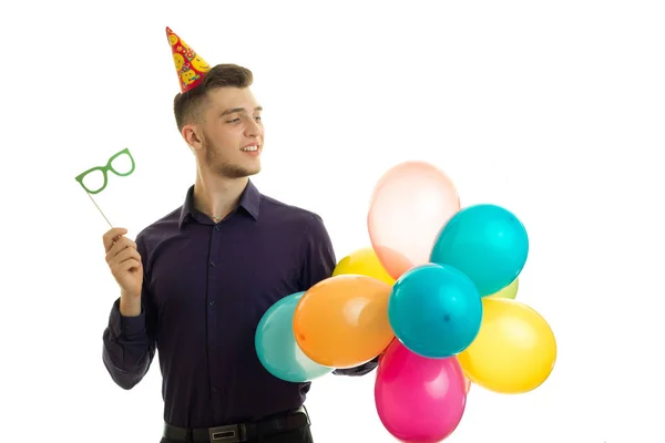 Bello giovane ragazzo è sorridente guarda di lato e tenendo un bicchieri di carta e palle d'aria — Foto Stock