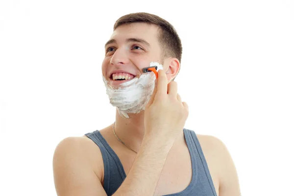 그의 얼굴에 거품을 가진 쾌활 한 젊은 남자는 기계 쪽으로 모양과 그의 수염을 면도 — 스톡 사진