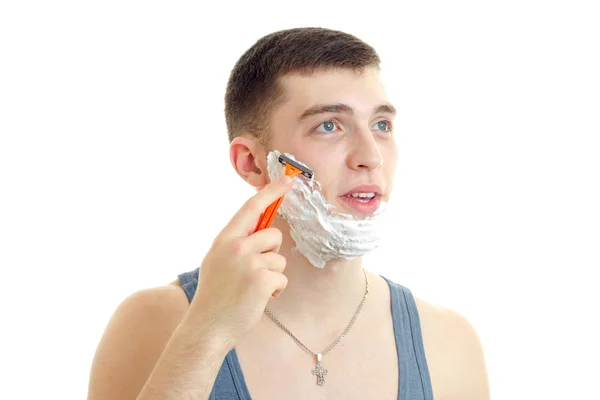 Retrato de un joven guapo con espuma en la cara que abrió la boca mira hacia arriba y se afeita la barba —  Fotos de Stock