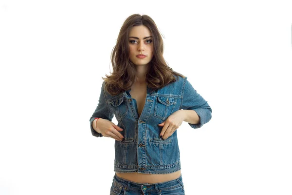 Jonge charmante brunette staat rechtop in een jeans jasje en kijkt naar een camera — Stockfoto