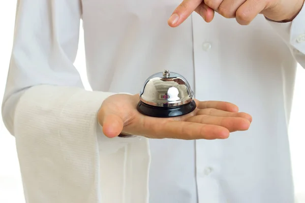 Camarero con una camisa blanca con una servilleta en la mano sostiene en el primer plano Palms Bell — Foto de Stock