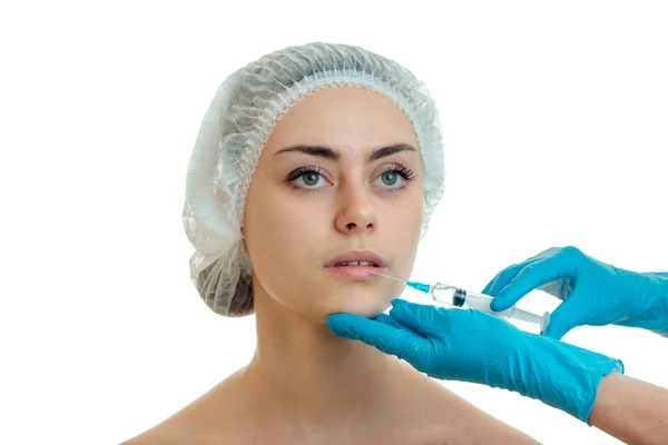 Retrato de una niña en una CAP médica que el médico inyecta la vacuna en la cara con las manos enguantadas —  Fotos de Stock