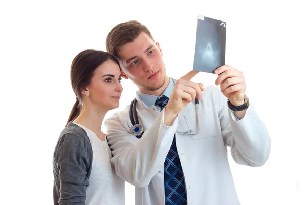 A young girl is standing next to a doctor in a white lab coat and he shows her an x-ray — Stock Photo, Image