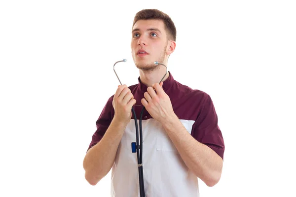 Jovem e forte médico de laboratório olha para cima e coloca um estetoscópio em seus ouvidos é isolado em um fundo branco — Fotografia de Stock