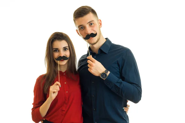 Bela menina e menino olhar para a direita e manter perto de seus rostos papel bigodes pretos — Fotografia de Stock