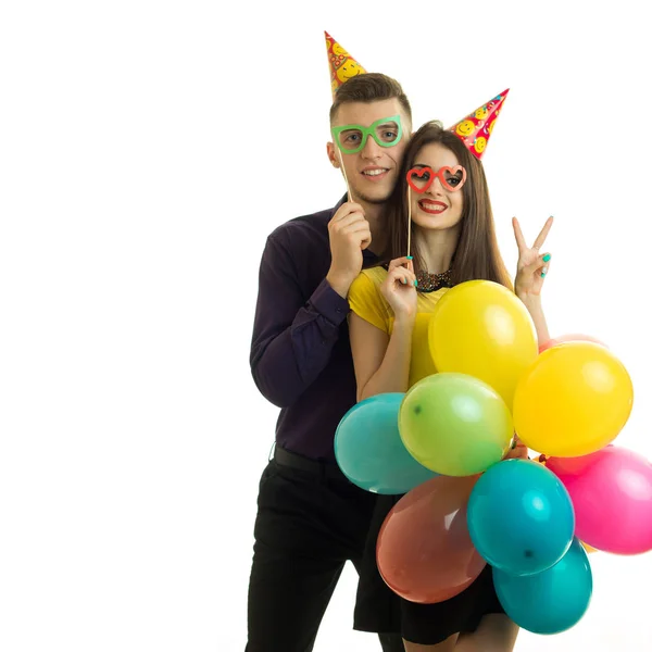 Sonriendo agradable chico y chica con conos en la cabeza sostenido cerca de personas maniquíes de papel y globos — Foto de Stock