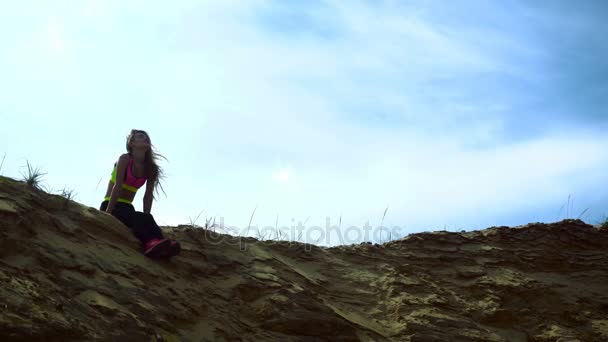 Sportlerin ruht sich auf dem sandigen Hügel aus — Stockvideo