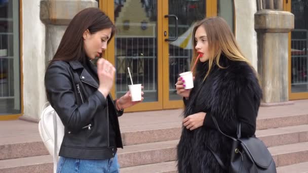 Две молодые девушки пьют кофе и разговаривают — стоковое видео
