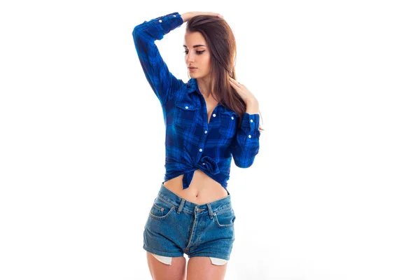 Beautiful young girls shirt in the box and in denim shorts looks away and raised her hand to head — Stock Photo, Image