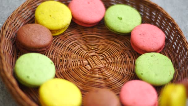 Chica pone un macarrón de colores galletas en un plato de mimbre — Vídeos de Stock