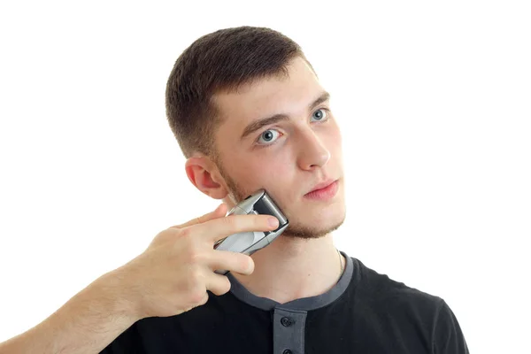 Portrait of attractive young guy who seriously shaves a beard trimmer close-up — Stock Photo, Image