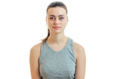 Gri bir t-shirt ve düz yukarıya ve ciddi kameraya bakarak duruyor toplanan saçlı güzel bir kadın portresi