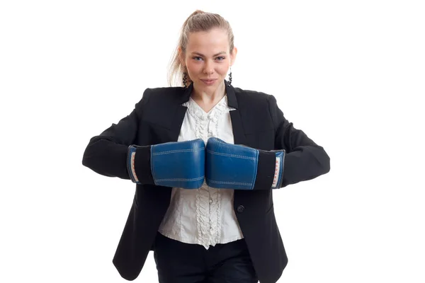 Hermosa joven rubia en un traje de oficina se queda de brazos cruzados en guantes de boxeo mira a la cámara y sonriendo — Foto de Stock