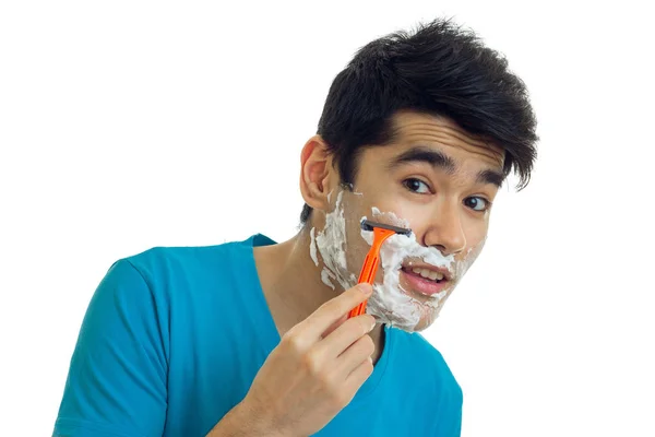 Bello giovane ragazzo con i capelli neri vale la pena aprire la bocca guarda nella fotocamera e radersi la barba primo piano — Foto Stock