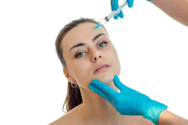 Косметолог в синих перчатках держит лицо молодой девушки и вводит инъекцию крупным планом — стоковое фото