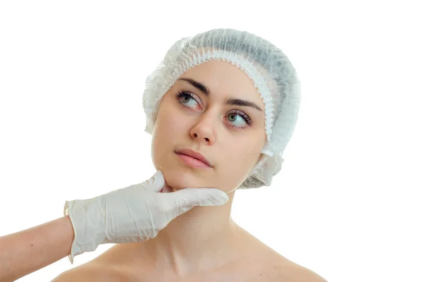 Cirujano en guante comprueba la cara de una hermosa chica en una gorra especial para el pelo de cerca —  Fotos de Stock