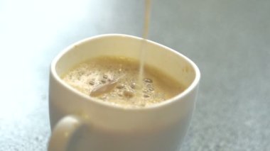 Bir fincan kahveye süt dökülür.