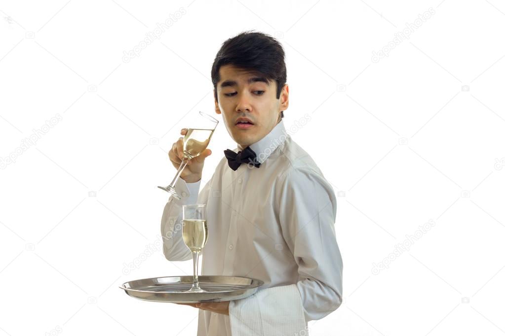 beautiful funny waiter stands sideways in a white shirt looks toward opened his mouth and holding a glass of wine