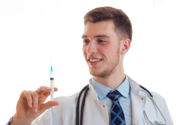 Bir şırınga yakın çekim elinde tutan gülümseyen genç bir doktor portresi