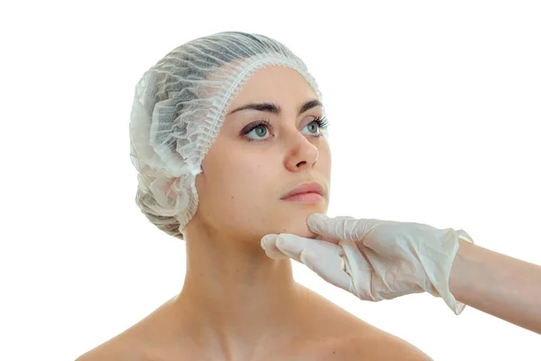 Young cute girl in medical hair hat came to the beautician and he looks at her face in white glove — Stock Photo, Image