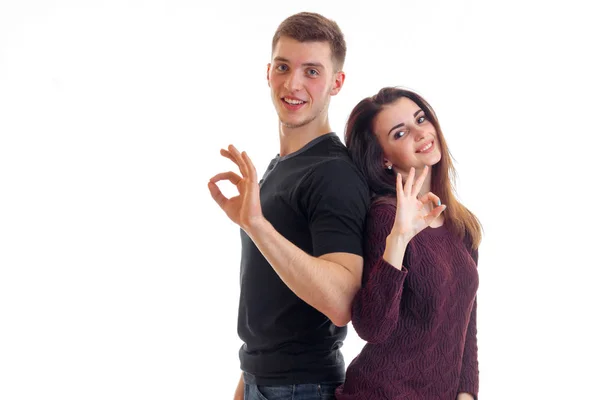 Belle fille et un gars sont debout à l'arrière à l'autre sourire regarder dans la caméra et montrer des gestes de mains — Photo