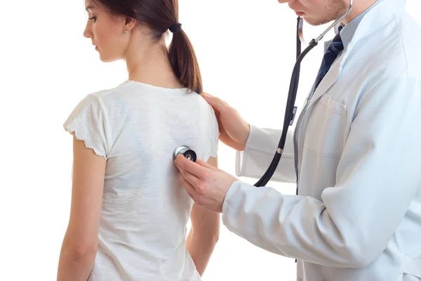 Um médico segurando um estetoscópio e ouve as costas dela de um close-up de uma jovem mulher — Fotografia de Stock