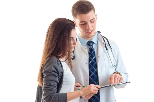 Молода дівчина з довгим волоссям дивиться лікар в одязі в планшеті ізольовано на білому тлі — стокове фото
