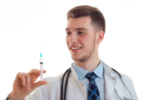 Retrato de um jovem médico sorridente que segura na mão uma seringa de perto — Fotografia de Stock