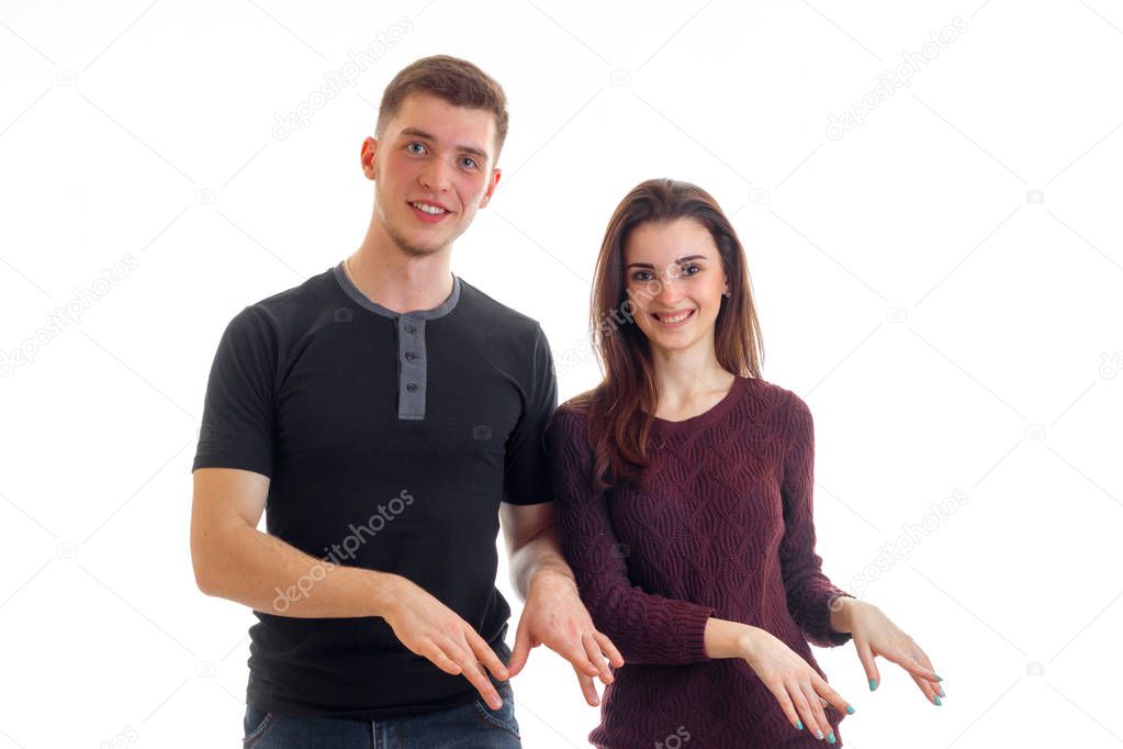 smiling beautiful young couple standing near look right and show hands gestures