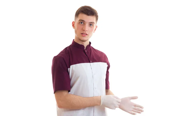 Молодой человек врач в форме и перчатках смотрит в камеру — стоковое фото