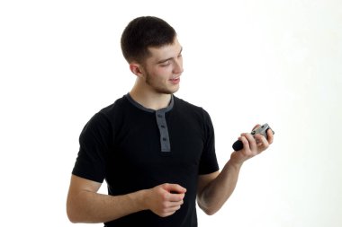 yakın çekim tıraş için bir kesme makinesi tutarak siyah t-shirt güzel gülümseyen genç adam