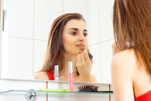 En charmig ung flicka gör makeup framför en spegel — Stockfoto