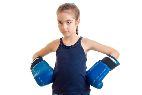 La niña está de pie en un gran adulto guantes de boxeo y mirando a la cámara —  Fotos de Stock