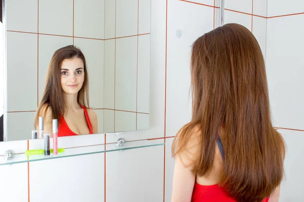 Ung vacker flicka tittar i spegeln — Stockfoto