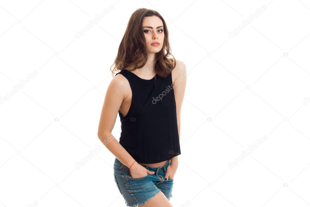 beautiful pin-up girl looks into the camera and keeps his hands in his pockets in denim shorts