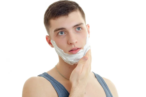 Retrato de un joven notable que mira hacia otro lado y se afeita la espuma en la barba de cerca —  Fotos de Stock