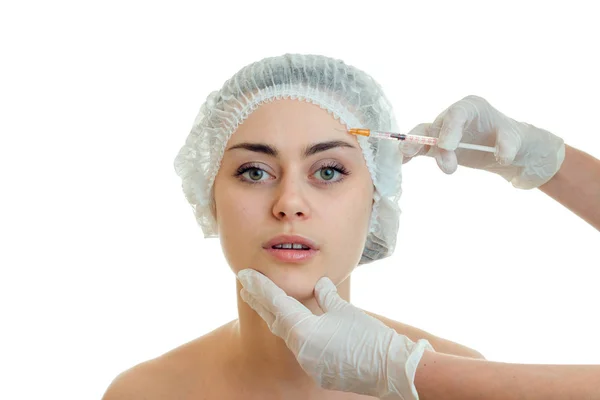 Bonito jovem sem maquiagem no cabelo médico Chapéu olha para a direita e o médico injeta a vacina em seu rosto um close-up — Fotografia de Stock