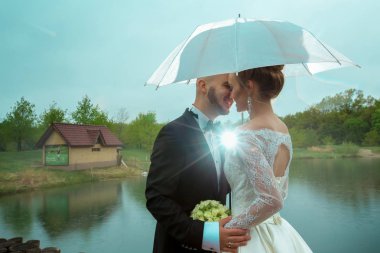 neşeli genç sadece evlenmiş çift bir şemsiye altında