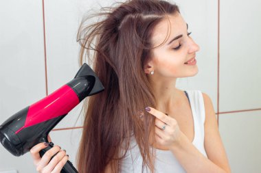 genç güzel kız Beyaz gömlekli saç kurutma makinesi kurur