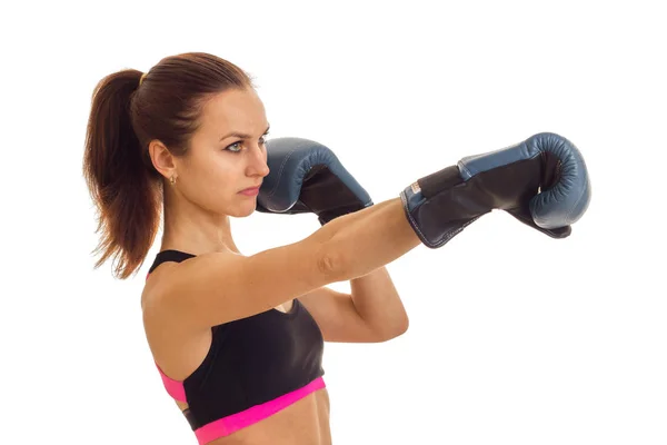 A young girl with the ponytail looks toward and reaches out his hands forward in boxing gloves — Stock Photo, Image