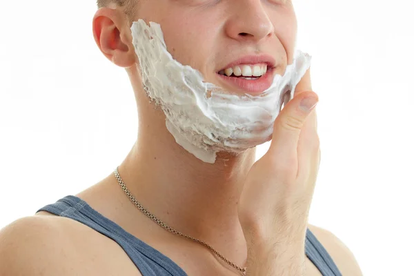 Joven chico sonríe y reparte la mano de afeitar espuma en la barba de cerca —  Fotos de Stock