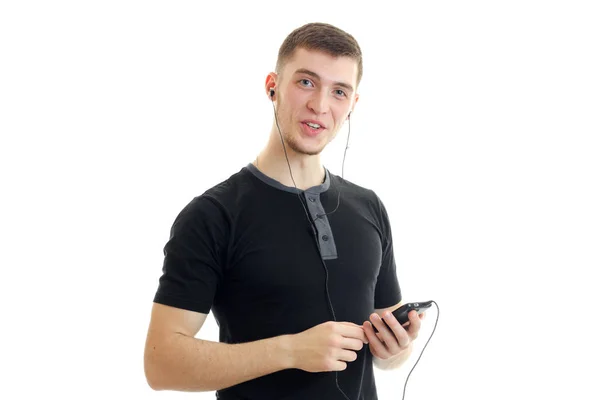 Okouzlující mladý muž v tričku poslouchá hudbu se sluchátky — Stock fotografie