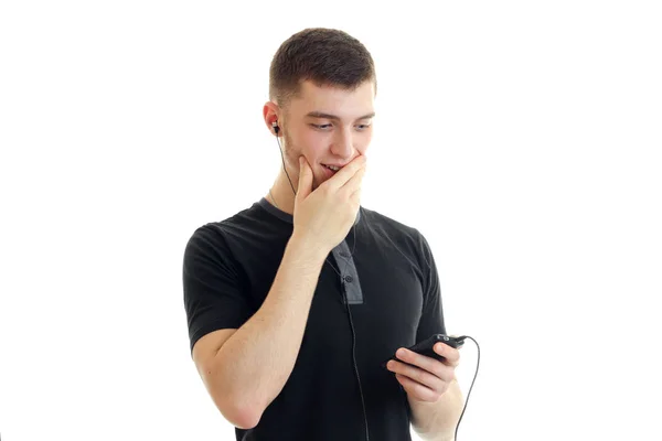 Young guy listens to music with headphones and closes the mouth hand — Stock Photo, Image