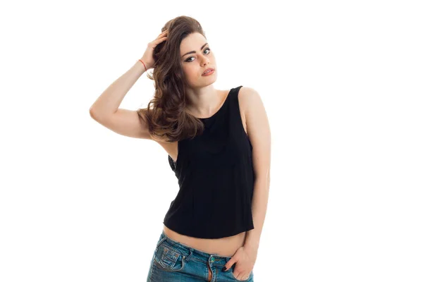 Amazing young brunette in black t-shirt looks into the camera and holds hand hair — Stock Photo, Image